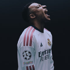 A football player in a white Real Madrid jersey with red stripes and FC Barcelona patches, captured mid-celebration against a dark background with EA Sports FC 27 Ultimate Edition branding at the top.